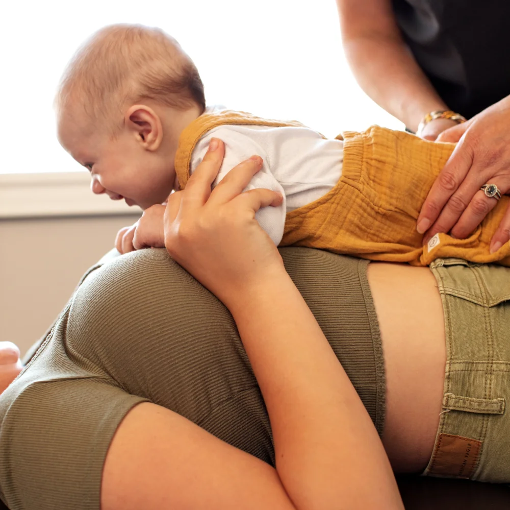 Mother lays with infant on treatment table