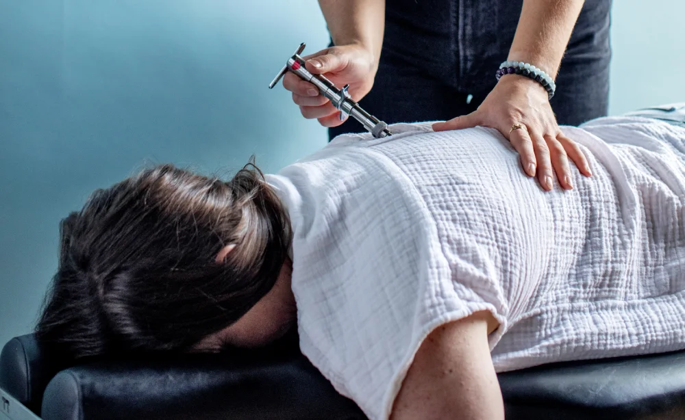 Female chiropractor performs assessment of upper back on patient